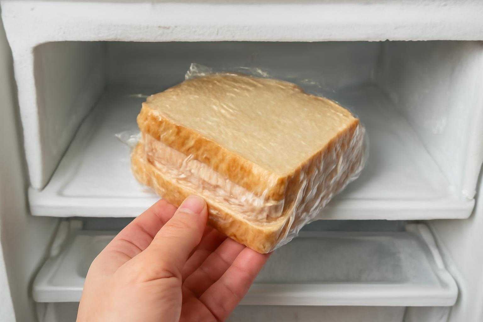 ラップに包まれたサンドイッチを冷凍室に入れている様子